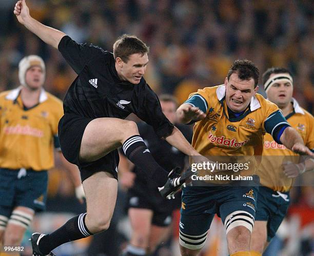 Andrew Mehrtens of the All Black's gets a kick away despite the charge down attempt from Owen Finegan of the Wallabies during the Tri Nations rugby...