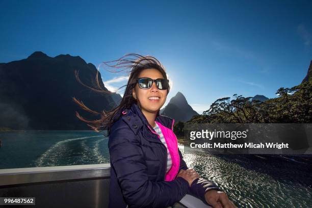 a girl poses for a photograph in the milford sound national park with the iconic mitre peak in the background. - mitre peak stock pictures, royalty-free photos & images