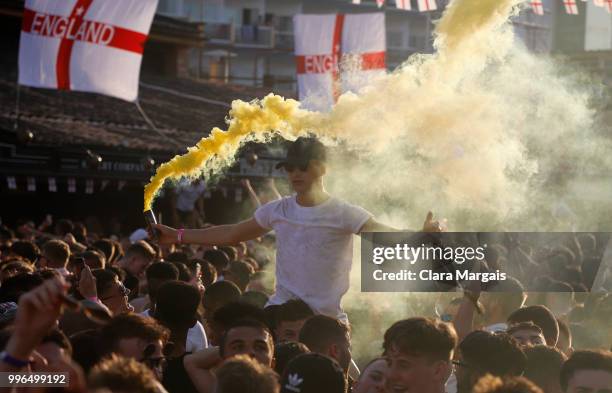 An England fans holds a smoke flare while watching the World Cup quarter-final match against Croatia on a giant screen in an outdoor viewing area on...
