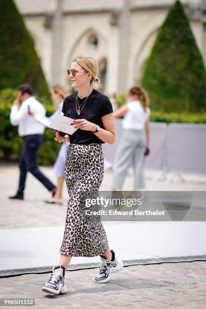 Guest wears a black t-shirt, sunglasses, a necklace, a leopard print skirt , Vuitton sneakers shoes, outside Dior, during Paris Fashion Week Haute...