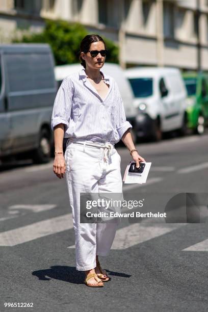 Guest wears a white shirt, white pants, sunglasses , outside Acne Studios, during Paris Fashion Week - Womenswear Fall Winter 2019, on July 1, 2018...