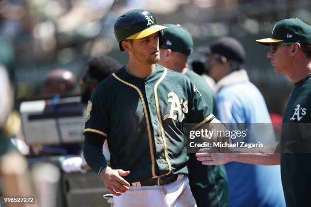 Chad Pinder of the Oakland Athletics is congratulated at the dugout during the game against the Los Angeles Angels of Anaheim at the Oakland Alameda...
