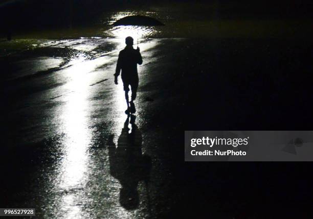 An indian man carrying umbrella, walks through a wet road during heavy rains in Allahabad on July 11,2018.