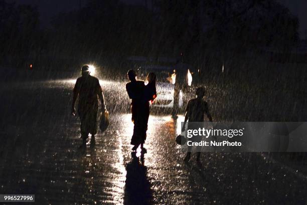 An indian family passes through heavy rains in Allahabad on July 11,2018 .