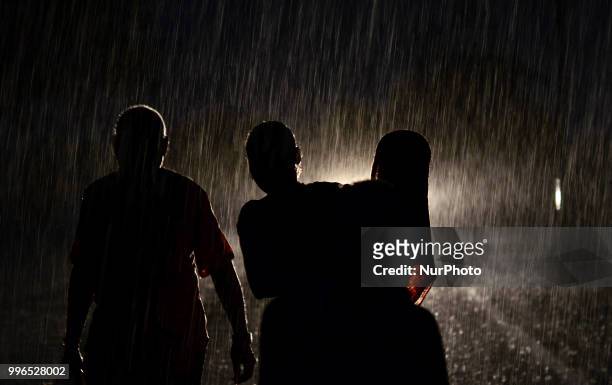 An indian family passes through heavy rains in Allahabad on July 11,2018 .