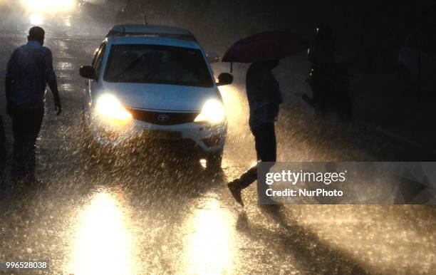 Indian local pedestrains cross a busy road during heavy rains in Allahabad on July 11,2018.