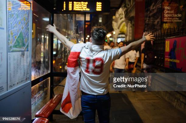 An England football fan raises his arms at a bus stop on Piccadilly following the country's exit from the World Cup, as disappointed supporters make...