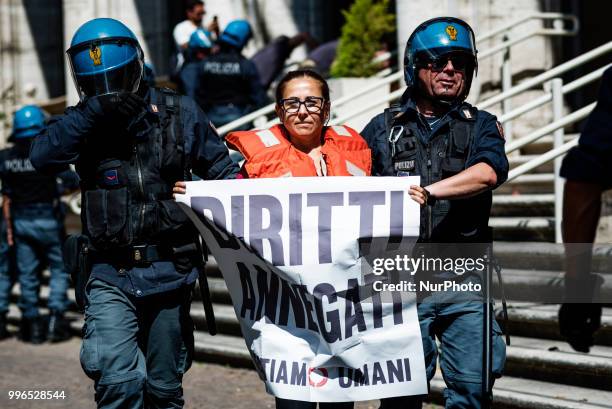 Italian police remove a 'We remain human' network activist holding a banner saying 'denied rights' that was chained in front of the Italian Minister...