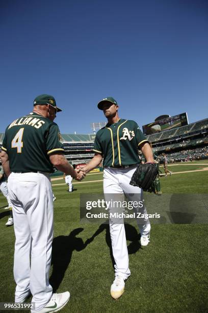 Third Base Coach Matt Williams and Blake Treinen of the Oakland Athletics celebrate on the field following the game against the Los Angeles Angels of...