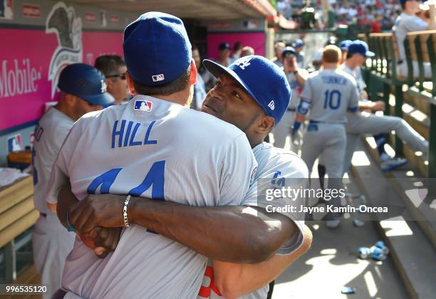 Yasiel Puig hugs Rich Hill of the Los Angeles Dodgers in the dugout before the game against the Los Angeles Angels of Anaheim at Angel Stadium on...