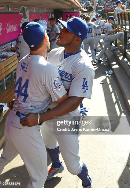 Yasiel Puig hugs Rich Hill of the Los Angeles Dodgers in the dugout before the game against the Los Angeles Angels of Anaheim at Angel Stadium on...