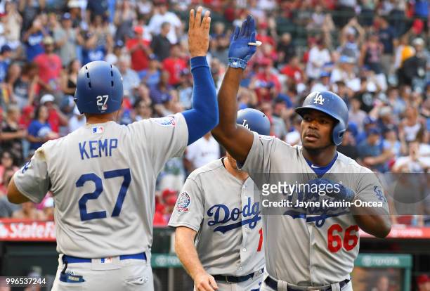 Yasiel Puig is greeted by Matt Kemp and Logan Forsythe of the Los Angeles Dodgers after hitting a three run home run in the second inning against the...