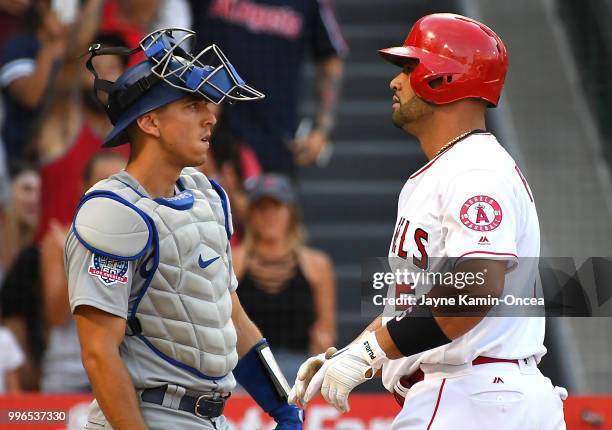 Austin Barnes of the Los Angeles Dodgers looks on as Albert Pujols of the Los Angeles Angels of Anaheim crosses the plate after hitting a solo home...