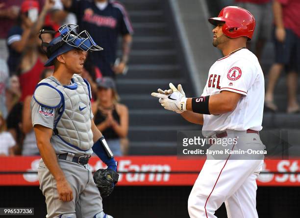 Austin Barnes of the Los Angeles Dodgers looks on as Albert Pujols of the Los Angeles Angels of Anaheim crosses the plate after hitting a solo home...