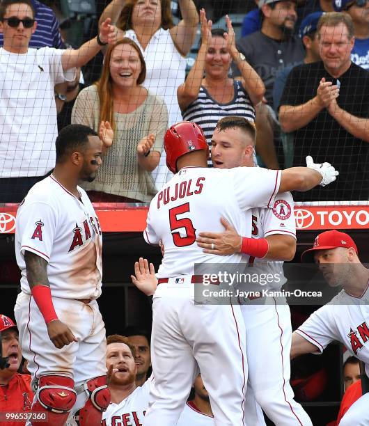 Albert Pujols is greeted by Mike Trout and Martin Maldonado of the Los Angeles Angels of Anaheim after hitting a solo home run to tie the game in the...