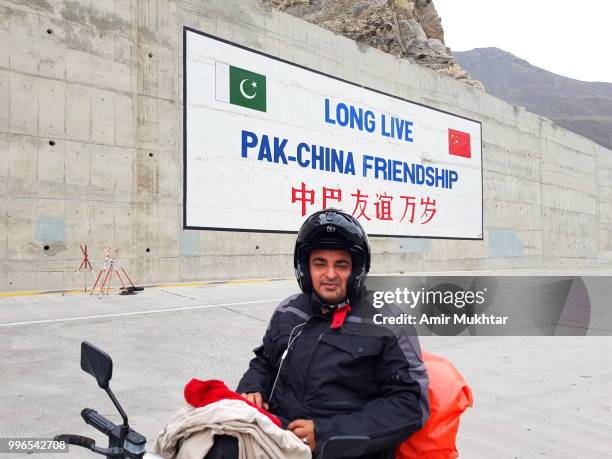 tourists on bike going to pass attabad lake tunnel - china pakistan stock-fotos und bilder