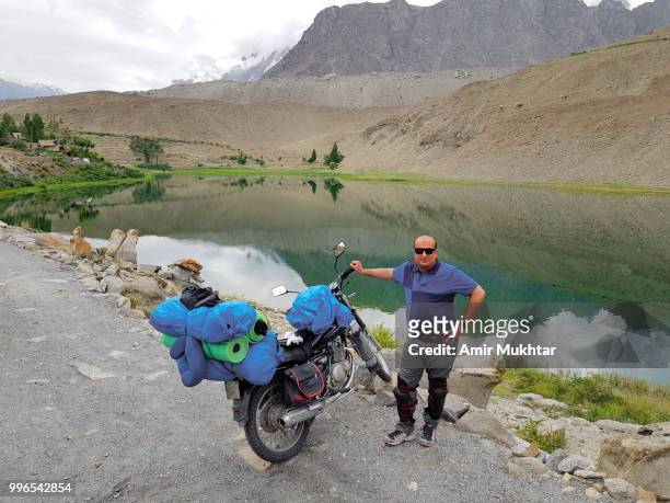 a biker and a beautiful view of borith lake with his motorcycle - amir mukhtar 個照片及圖片檔