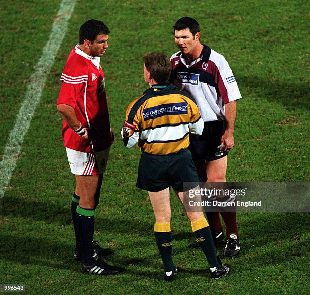 Captain Martin Johnson of the British Lions and captain Daniel Herbert of the Queensland Reds are spoken to by referee Stuart Dickinson after a fight...