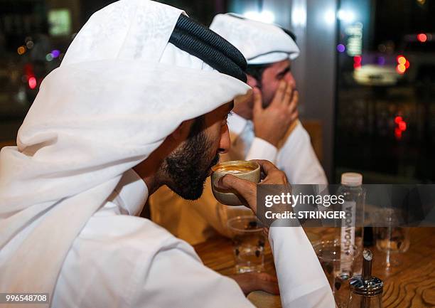 Customer sips a cup of coffee as he sits in the "Flat White" cafe in the Qatari capital Doha's Tawar Mall on June 8, 2018. - Tawar Mall looks like...