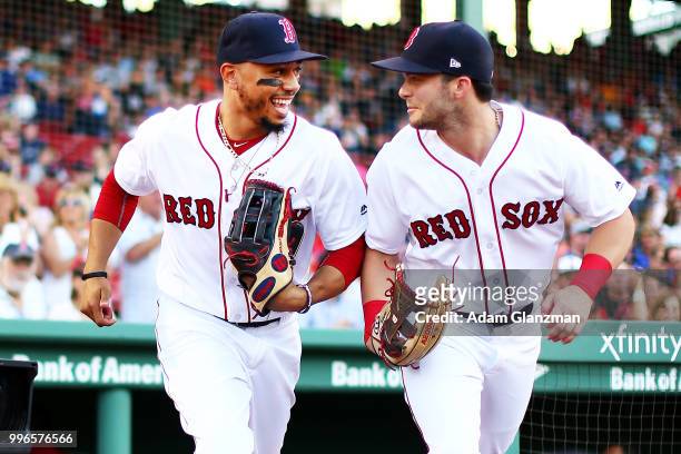 Mookie Betts and Andrew Benintendi of the Boston Red Sox take the field before a game against the Texas Rangers at Fenway Park on JULY 9, 2018 in...