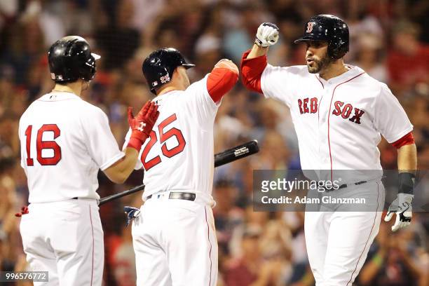 Martinez high fives Steve Pearce and Andrew Benintendi of the Boston Red Sox after hitting a three-tun home run in the eighth inning of a game...