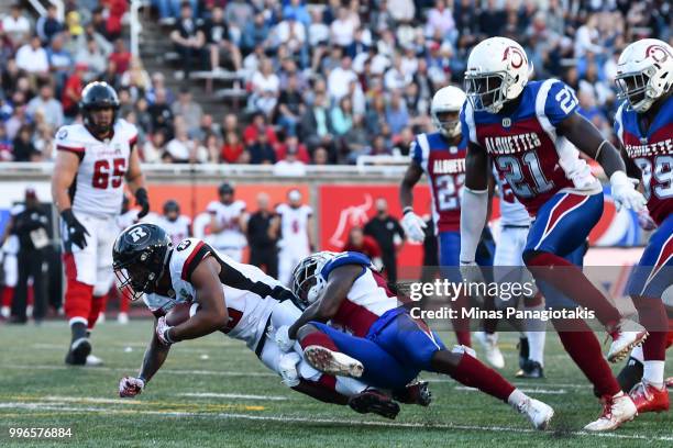 Defensive back Dominique Ellis of the Montreal Alouettes tackles wide receiver Noel Thomas Jr. #18 of the Ottawa Redblacks during the CFL game at...