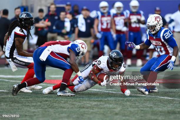 Linebacker Kevin Brown II of the Ottawa Redblacks falls between wide receiver Ernest Jackson and running back Tyrell Sutton of the Montreal Alouettes...