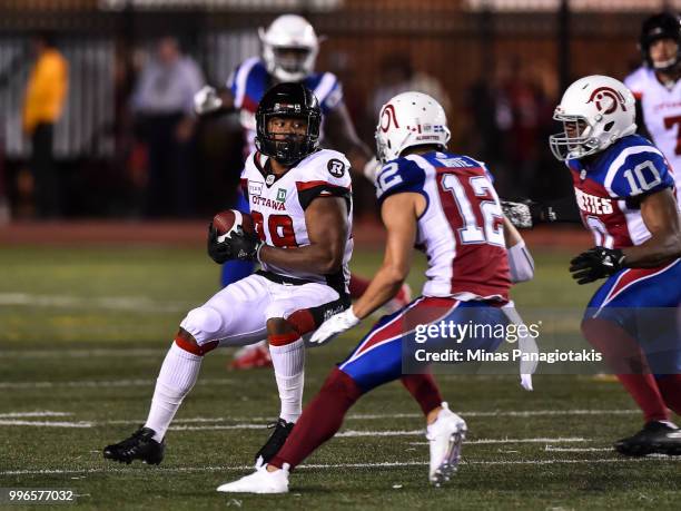 Running back William Powell of the Ottawa Redblacks protects the ball from defensive back Mitchell White of the Montreal Alouettes during the CFL...