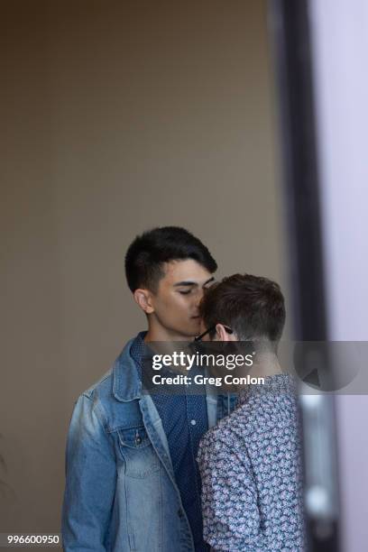 young man kissing another young man on the forehead. - first kiss imagens e fotografias de stock