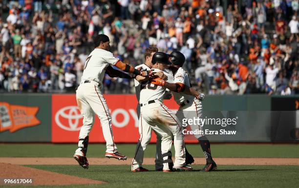 Buster Posey of the San Francisco Giants is congratulated by teammates after hitting the game winning hit in the bottom of the 13th inning to beat...