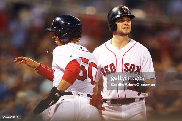 Mookie Betts and Andrew Benintendi of the Boston Red Sox react after scoring in the fifth inning of a game against the Texas Rangers at Fenway Park...