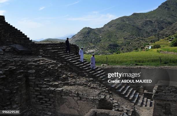 This photo taken on April 27, 2018 shows Pakistani visitors walking down stairs to see a centuries-old stupa, a dome-shaped Buddhist monument, in the...