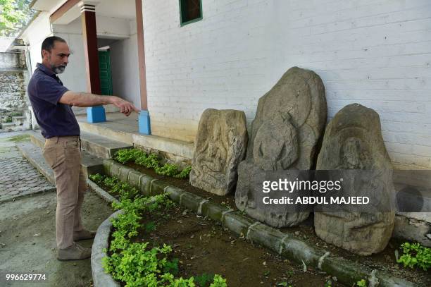 This photo taken on April 27, 2018 shows Italian archaeologist Luca Maria Olivieri pointing towards Buddhist statues at an archaeological site in the...