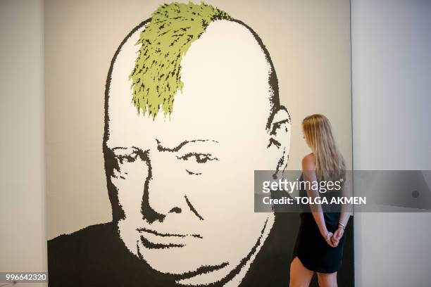 Gallery assistant poses with 'Turf War' 2003 artwork by Banksy at Lazinc Gallery in London on July 11, 2018. - The exhibition opens to the public on...