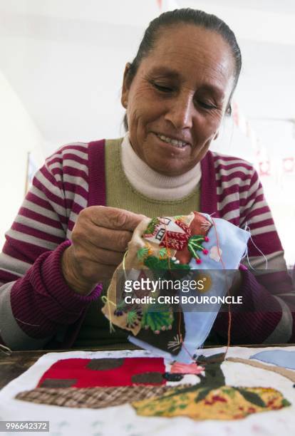 Woman displaced from her community in the Andes during Peru's conflict against the Maoist Shining Path guerrilla, works on an "Arpillera" -a...