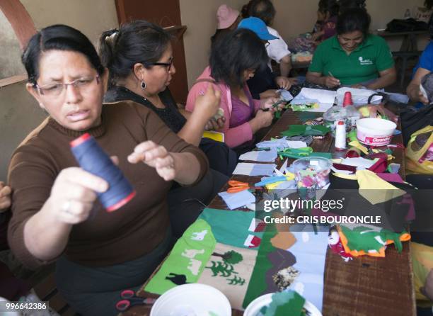 Women displaced from their communities in the Andes during Peru's conflict against the Maoist Shining Path guerrilla, work on an "Arpillera" -a...
