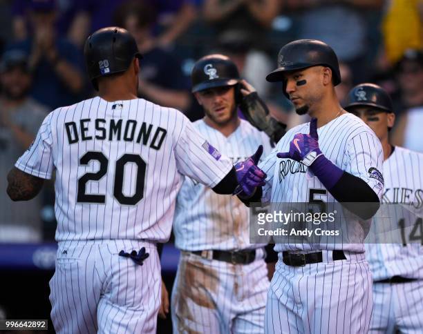 Colorado Rockies first baseman Ian Desmond celebrates at home plate with Carlos Gonzalez and Trevor Story, #27, center, after hitting a three-run...