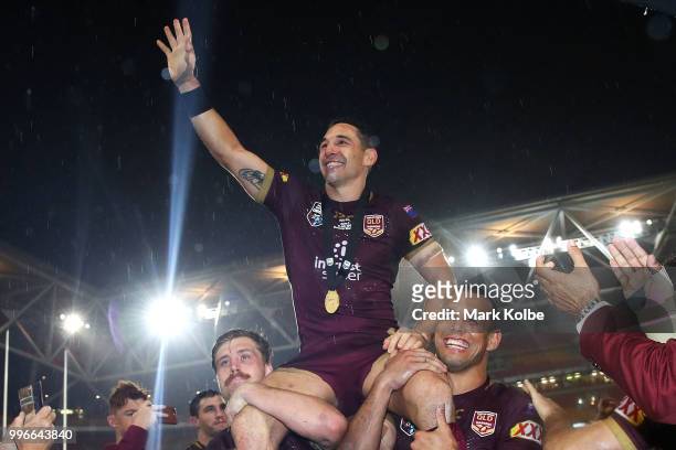 Billy Slater of Queensland waves to the crowd as he is chaired from the field by Cameron Munster and Will Chambers of Queensland after his final game...