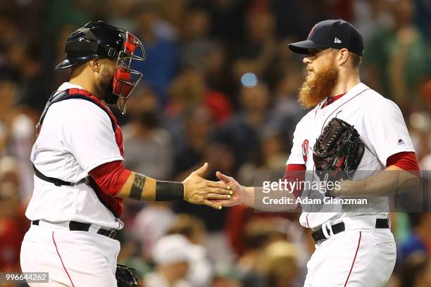 Craig Kimbrel high fives Sandy Leon of the Boston Red Sox after a victory over the Texas Rangers at Fenway Park on July 11, 2018 in Boston,...