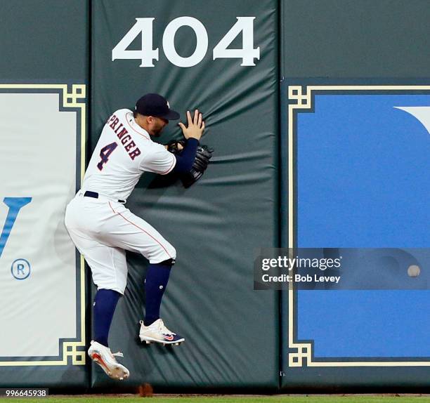 George Springer of the Houston Astros slams into the wall as he attempts to catch a line drive from Khris Davis of the Oakland Athletics in the sixth...