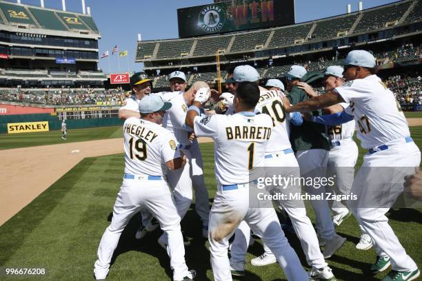 Jonathan Lucroy of the Oakland Athletics is mobbed by teammates after hitting a walkoff single during the game against the Los Angeles Angels of...