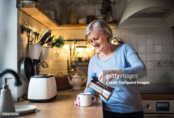 senior woman making coffee in the kitchen at home. - old toaster stock pictures, royalty-free photos & images