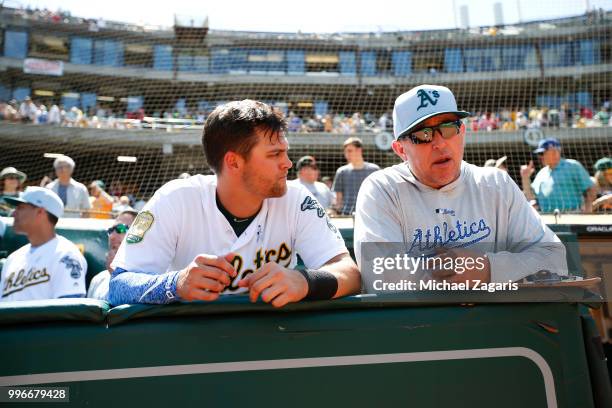 Chad Pinder and Hitting Coach Darren Bush of the Oakland Athletics talk in the dugout during the game against the Los Angeles Angels of Anaheim at...