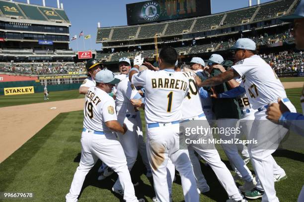 Jonathan Lucroy of the Oakland Athletics is mobbed by teammates after hitting a walkoff single during the game against the Los Angeles Angels of...