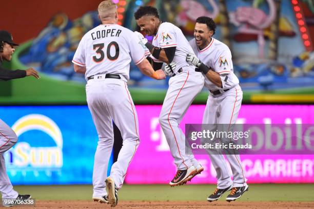 Yadiel Rivera and Garrett Cooper of the Miami Marlins celebrate with Starlin Castro after hitting a walk off single in the twelfth inning against the...