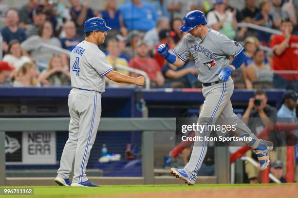 Blue Jays infielder Justin Smoak is congratulated by third base coach Luis Rivera after hitting a solo home run during the game between Atlanta and...