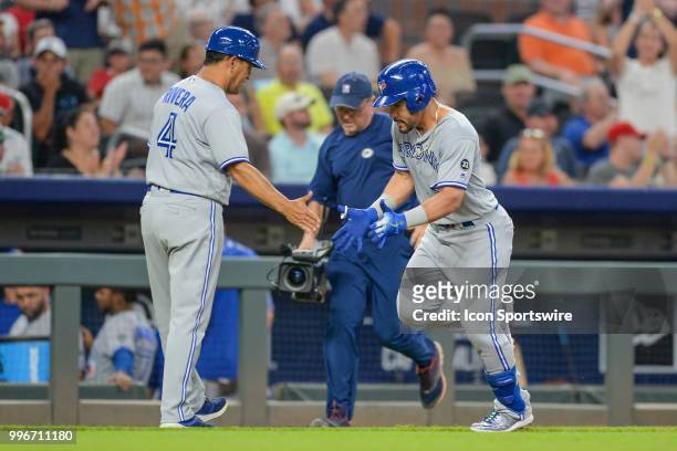 Blue Jays infielder Devon Travis is congratulated by third base coach Luis Rivera after hitting a grand slam home run during the game between Atlanta...