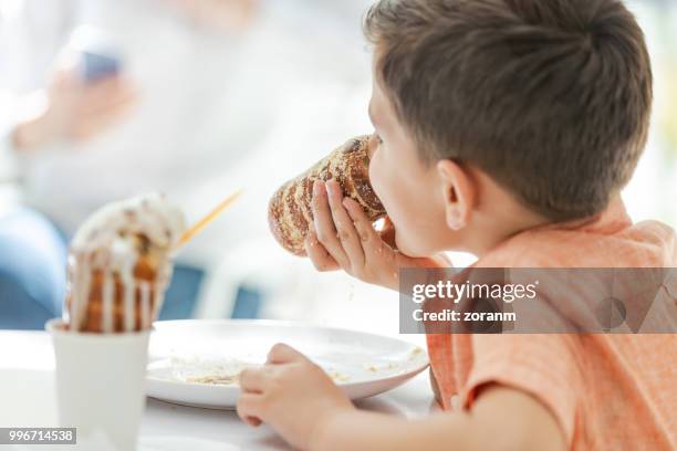 biting crusty chimney cake - trying new food stock pictures, royalty-free photos & images