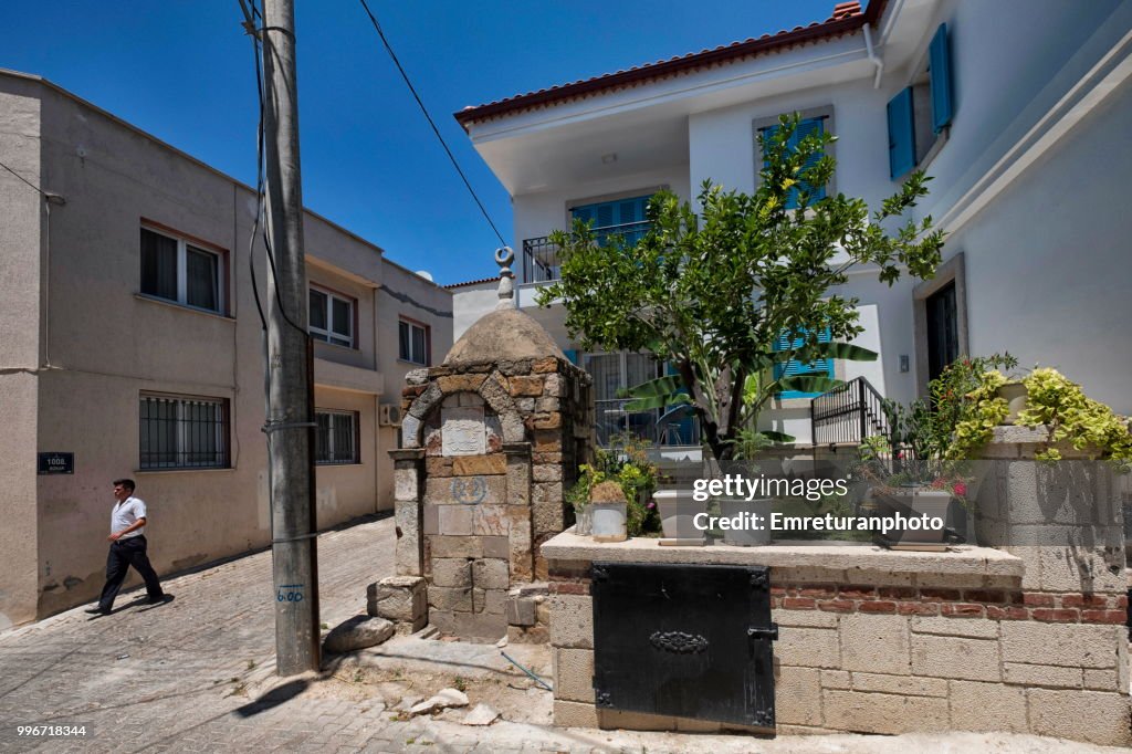 Man walking at a street with a historic fountain,Cesme.
