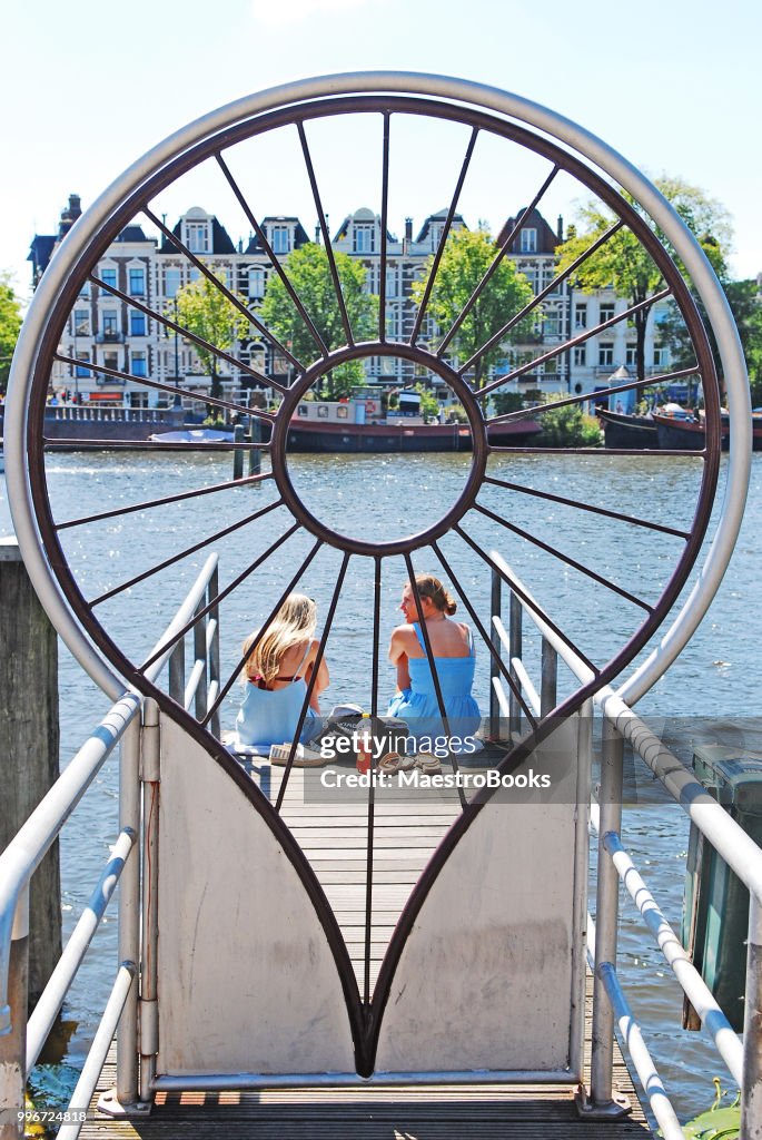 Zwei glückliche junge Frauen sprechen auf dem Amstel Fluss Pier.